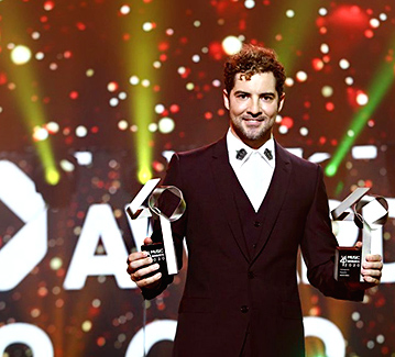 Fotografia de um cantor com o troféu