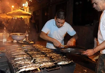 homem a grilhar sardinhas