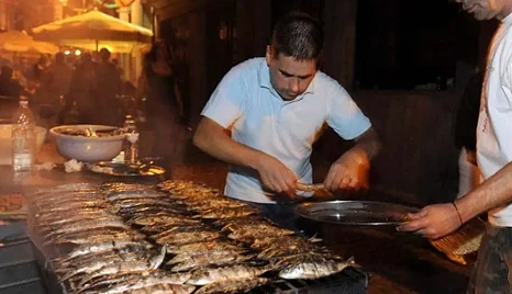homem a grilhar sardinhas