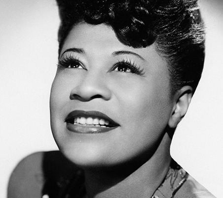 imagem a preto e branco de ella fitzgerald a olhar para cima e com um sorriso esperaçonso