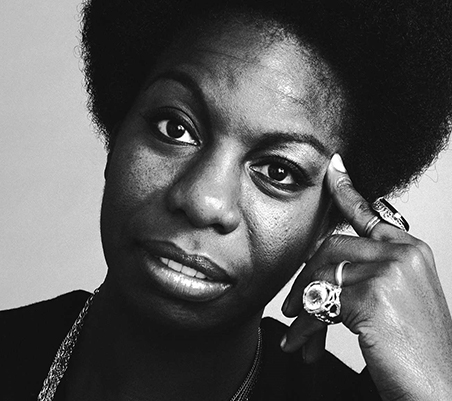 imagem a preto e branco de nina simone a olhar para a camara e com a cabeca apoiada na mao